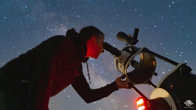 Cena Sotto le Stelle Persona che osserva le stelle attraverso un telescopio di notte