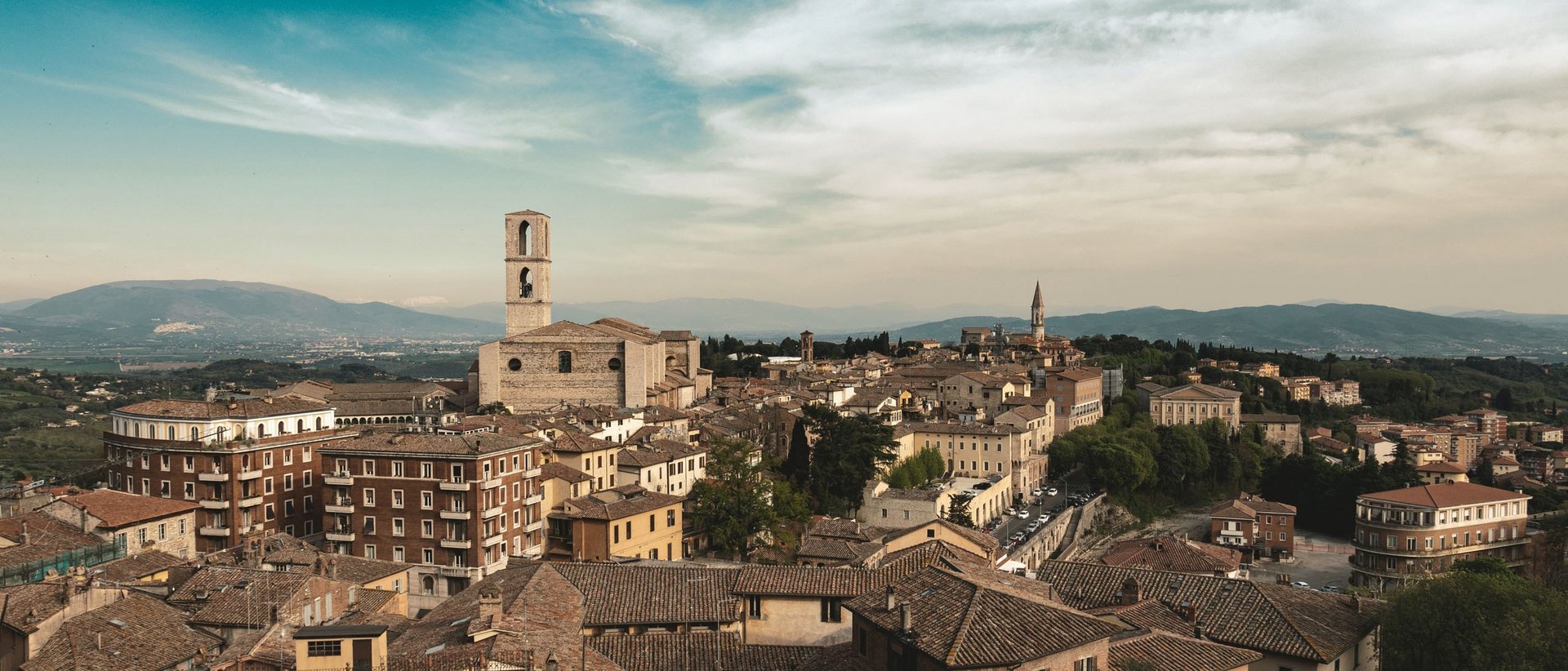 La Basilica di San Francesco ad Assisi Veduta panoramica della città con edifici storici e campanili sotto un cielo parzialmente nuvoloso