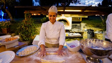 Cena Sotto le Stelle Chef che prepara pasta fresca in un ambiente esterno al tramonto
