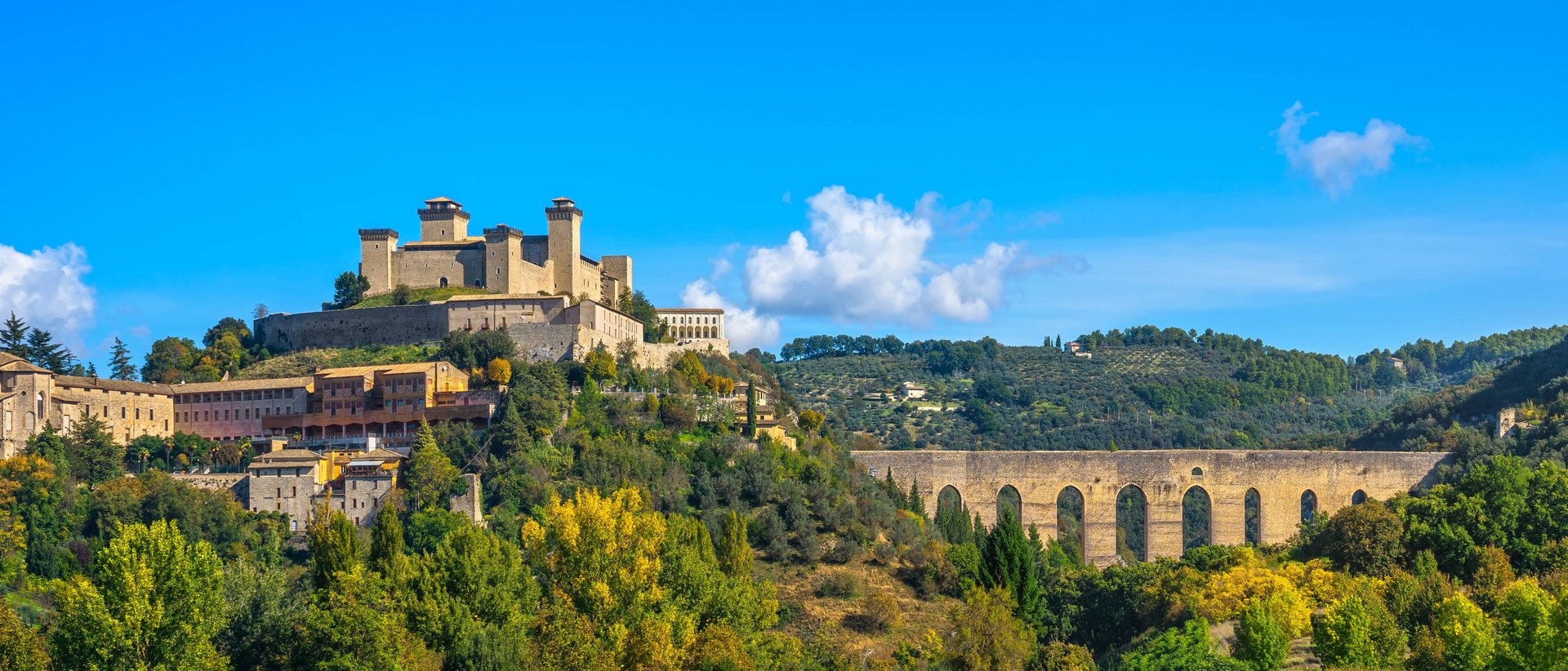 La Basilica di San Francesco ad Assisi Castello medievale e acquedotto in collina verde sotto un cielo blu