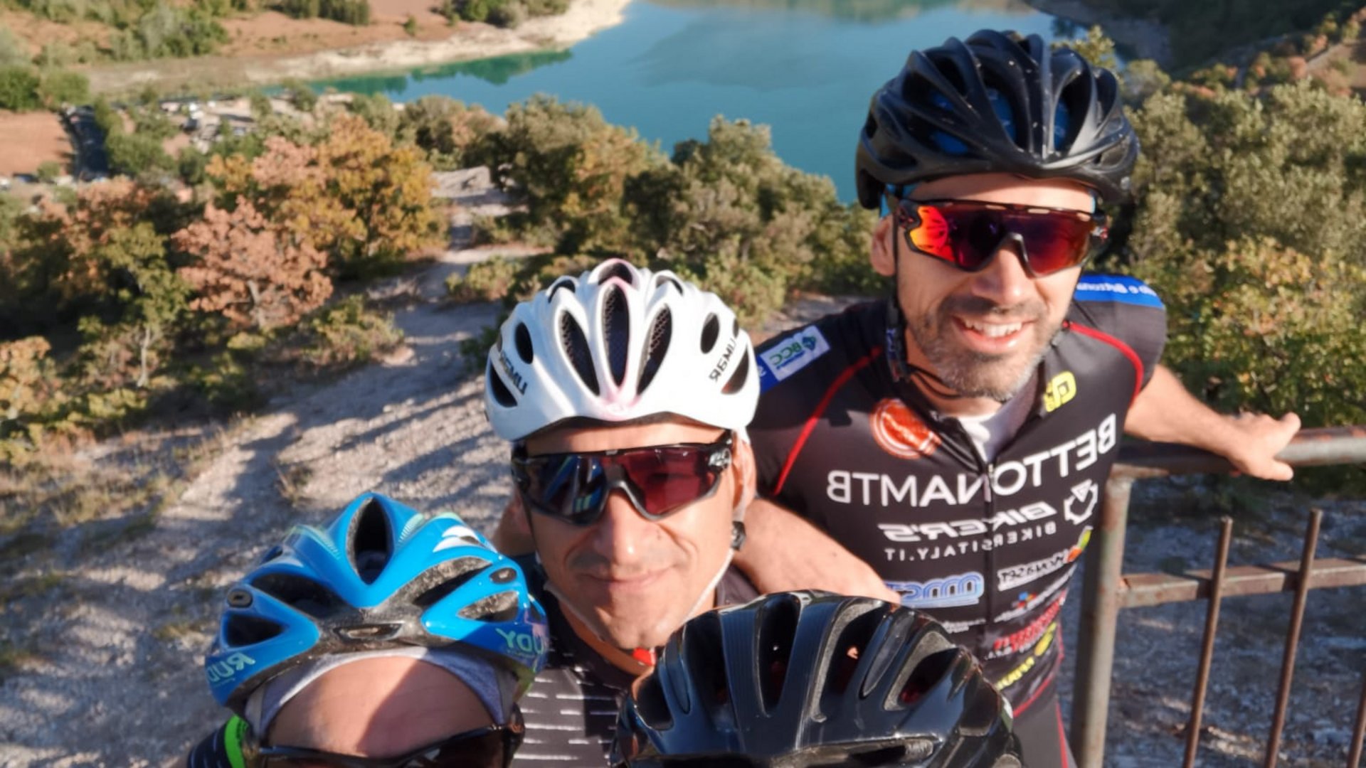 Vacanze Bike ad Assisi unico Italy bike hotels in Umbria Quattro ciclisti sorridenti con caschi davanti a un lago di montagna