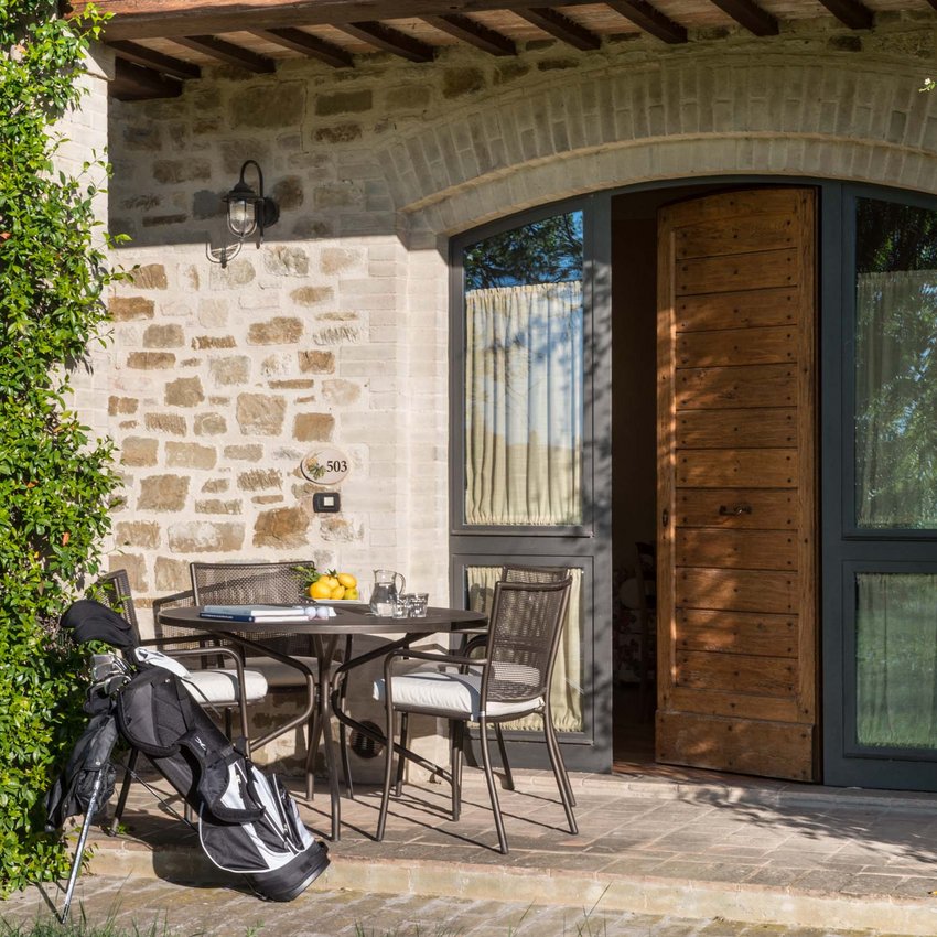 Un resort vicino ad Assisi indimenticabile Portico con tavolo e sedie, sacco da golf appoggiato, porta in legno semiaperta