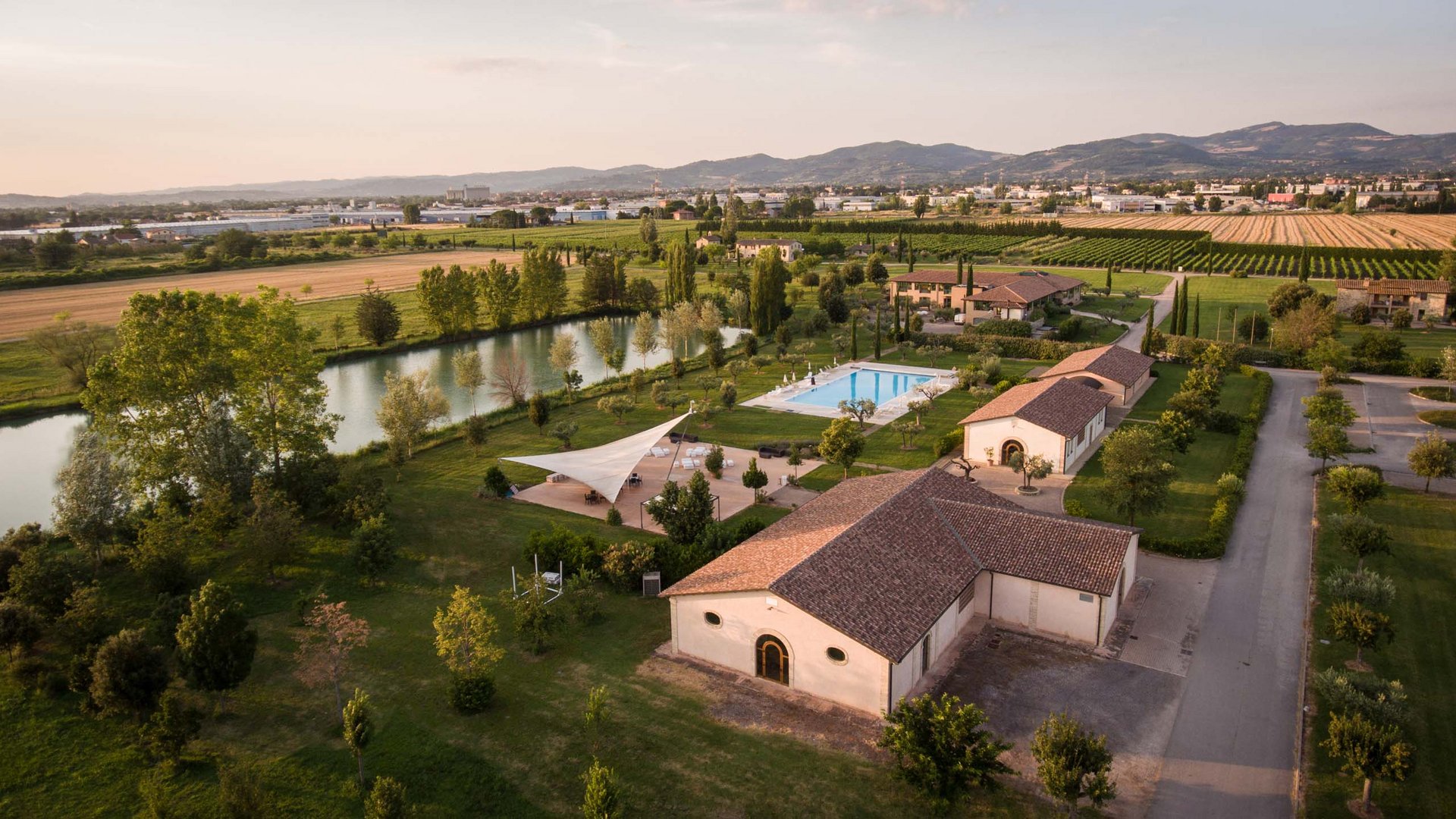 La missione di Valle di Assisi Veduta aerea di azienda agricola con piscina e lago circondata da campi verdi e montagne