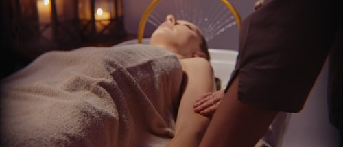 Gift Voucher Idee Regalo Festa della Mamma e anniversari dalla SPA benessere ai massaggi con cena. Donna che riceve massaggio rilassante in spa con candele accese sullo sfondo