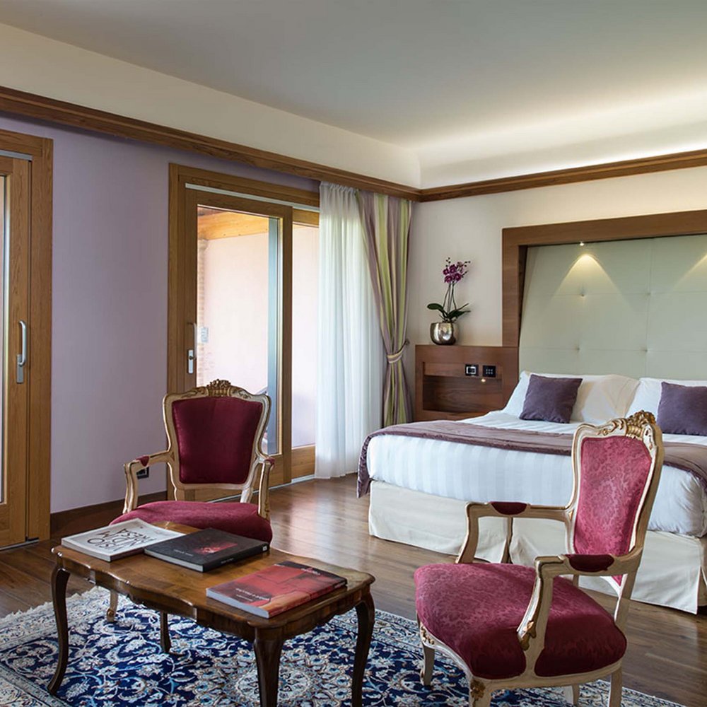 Suite con Area SPA interna Camera elegante con letto grande, poltrone rosse e vista sulla terrazza