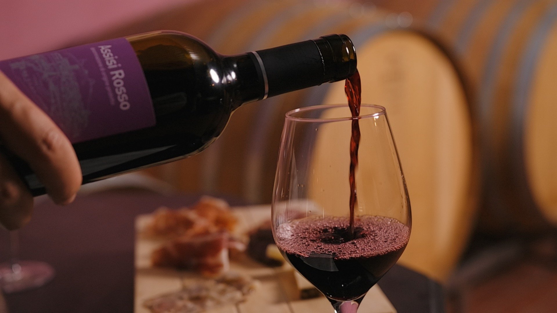 Pranzo di Pasquetta ad Assisi con Percorso SPA A Valle di Assisi, il Ristorante Recanto vi aspetta Vino rosso versato in bicchiere con sfondo di botti di legno