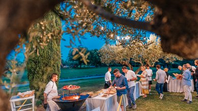 Cena Sotto le Stelle Persone che si servono a un buffet all'aperto con chef che cucina alla griglia