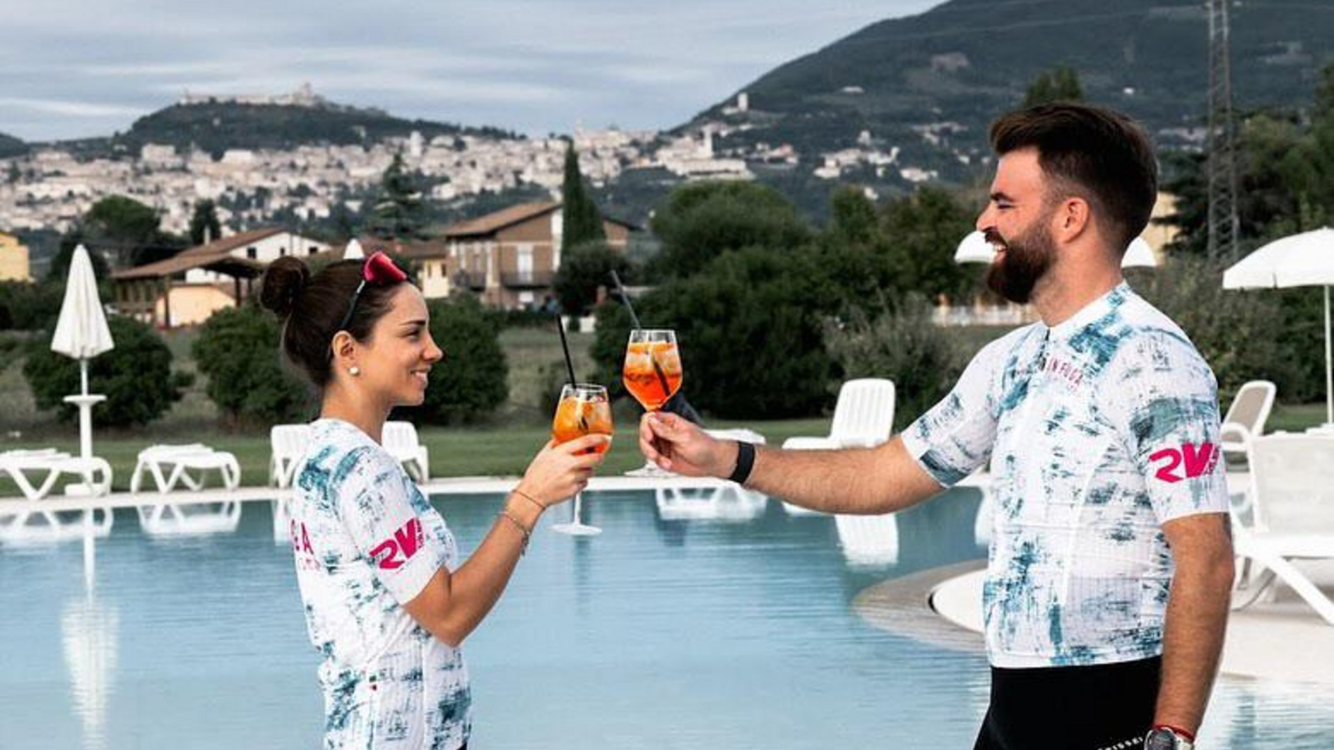 Vacanze Bike ad Assisi unico Italy bike hotels in Umbria Due persone brindano con cocktail vicino a una piscina all'aperto con colline sullo sfondo