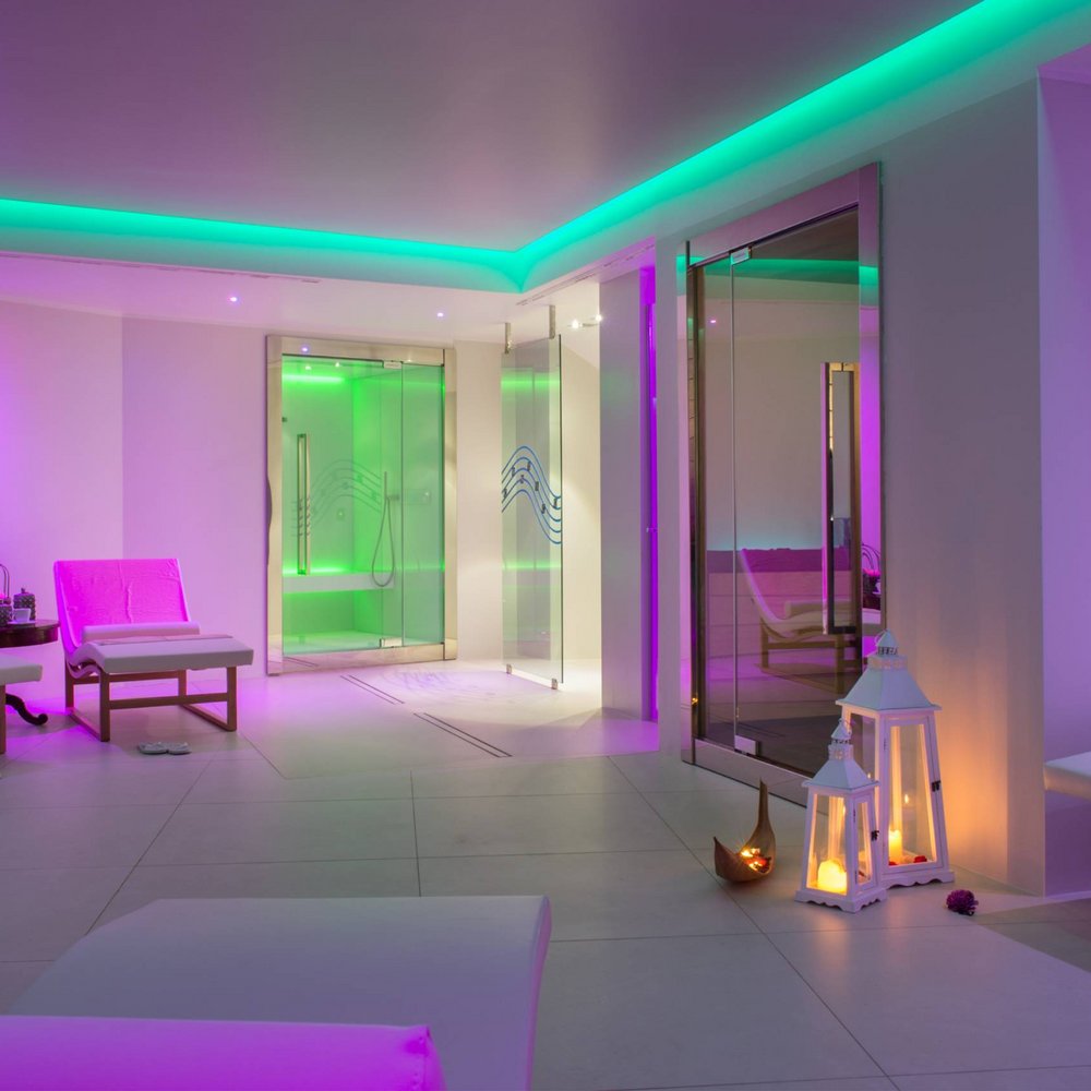 Private SPA in Umbria Assisi Wellness & SPA Percorso Benessere di Coppia Interno di una spa con luci soffuse viola e verde, lettini e lanterne accese
