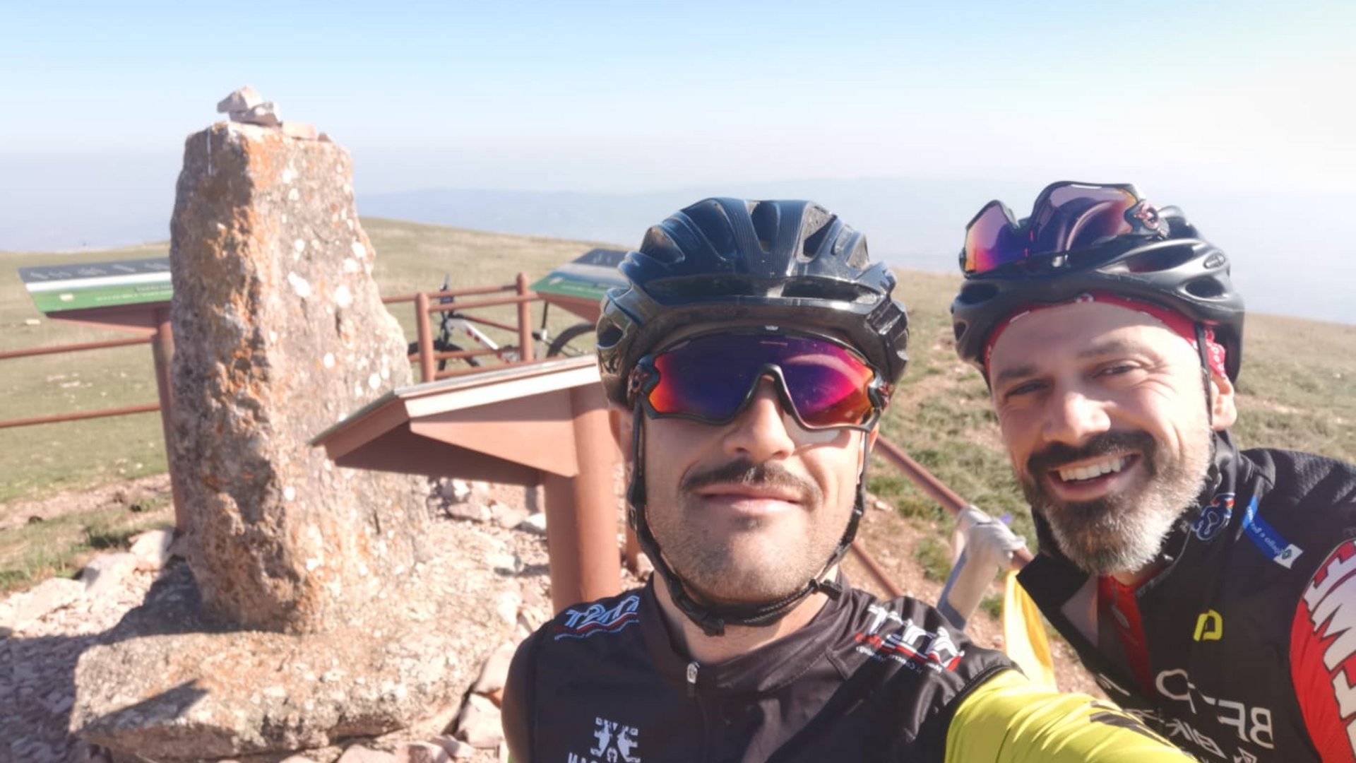 Vacanze Bike ad Assisi unico Italy bike hotels in Umbria Due ciclisti con caschi sorridono davanti a una pietra e cartelli informativi in montagna