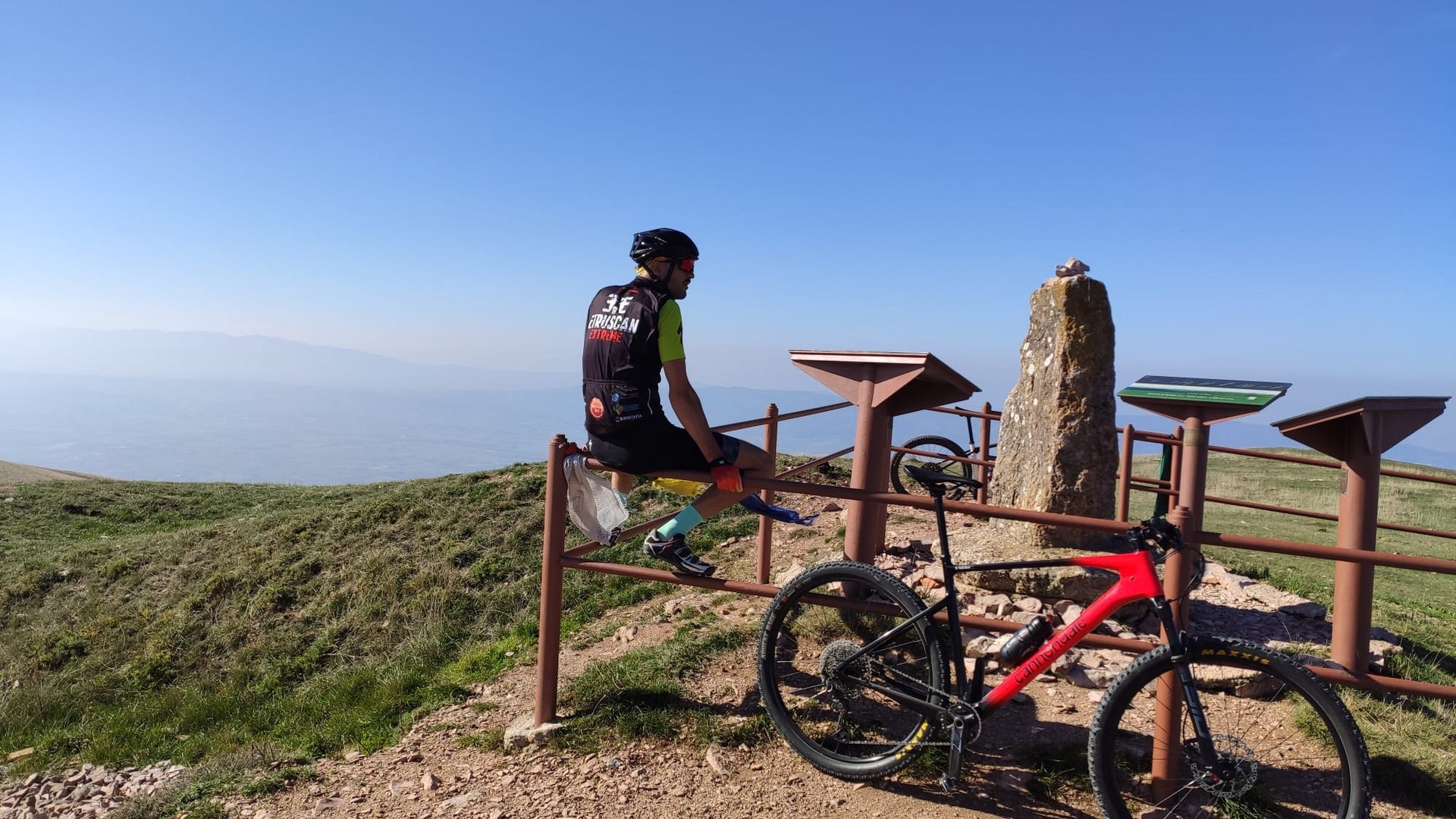 Vacanze Bike ad Assisi unico Italy bike hotels in Umbria Ciclista seduto su una recinzione con bici rossa su una collina panorama