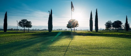 La missione di Valle di Assisi Bandiera su campo da golf al tramonto con alberi e cielo limpido