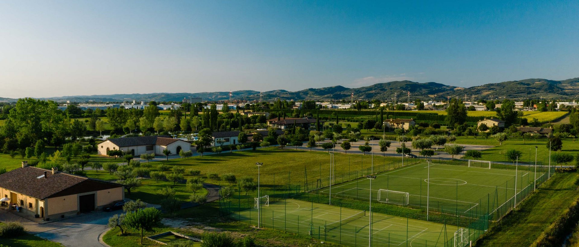 La missione di Valle di Assisi Campi sportivi in un'area verde con montagne sullo sfondo