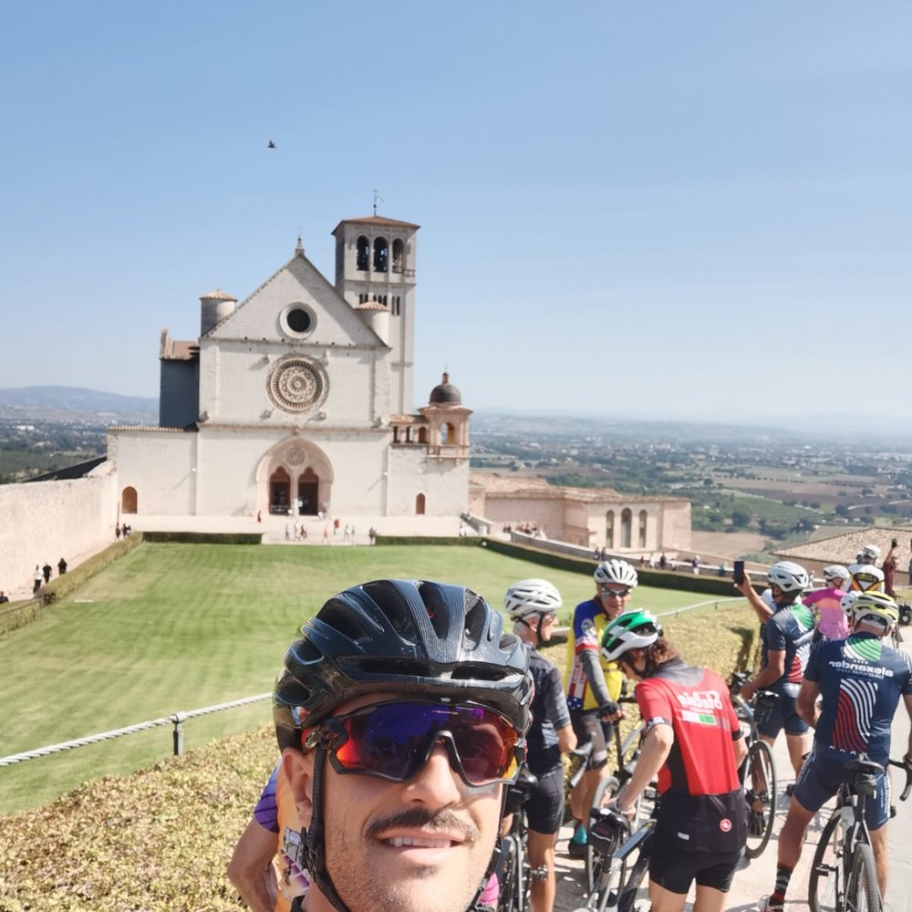 Vacanze Bike ad Assisi unico Italy bike hotels in Umbria Gruppo di ciclisti davanti alla Basilica di San Francesco ad Assisi sotto un cielo sereno