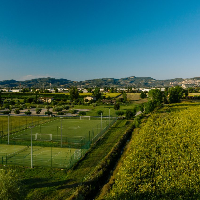Un hotel accessibile, in Umbria, con una marcia in più Campi da calcio verdi vicino a un campo giallo e colline sullo sfondo