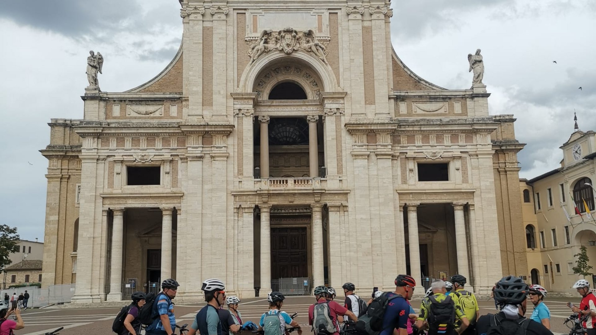 Vacanze Bike ad Assisi unico Italy bike hotels in Umbria Gruppo di ciclisti davanti a una grande chiesa storica con statua dorata in cima
