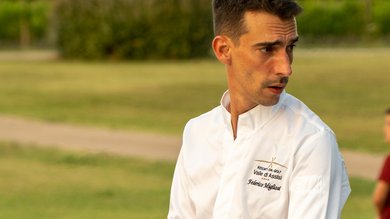 Cena Sotto le Stelle Chef in giacca bianca che prepara cibo all'aperto in un ambiente naturale