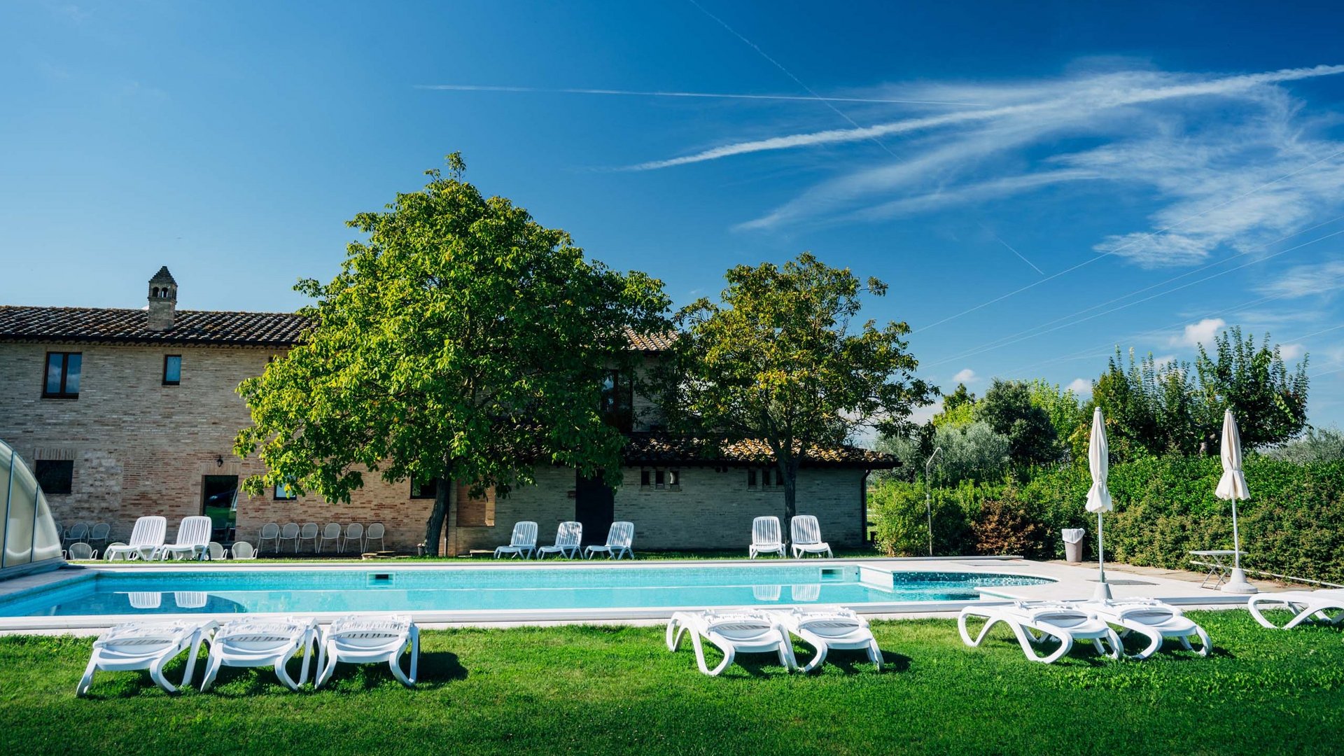 Un hotel a Santa Maria degli Angeli, Assisi? No, molto di più Piscina all'aperto con lettini e ombrelloni in un giardino soleggiato davanti a una casa