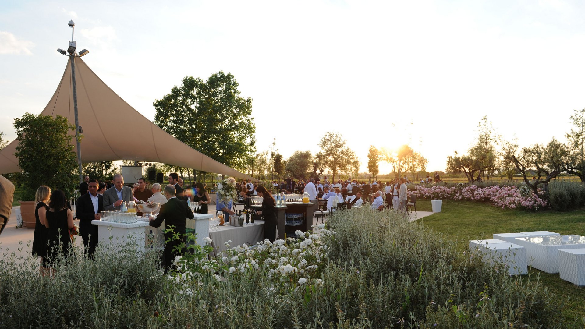 La vostra location per matrimoni ad Assisi Evento all'aperto al tramonto con persone che socializzano e tavoli con bevande