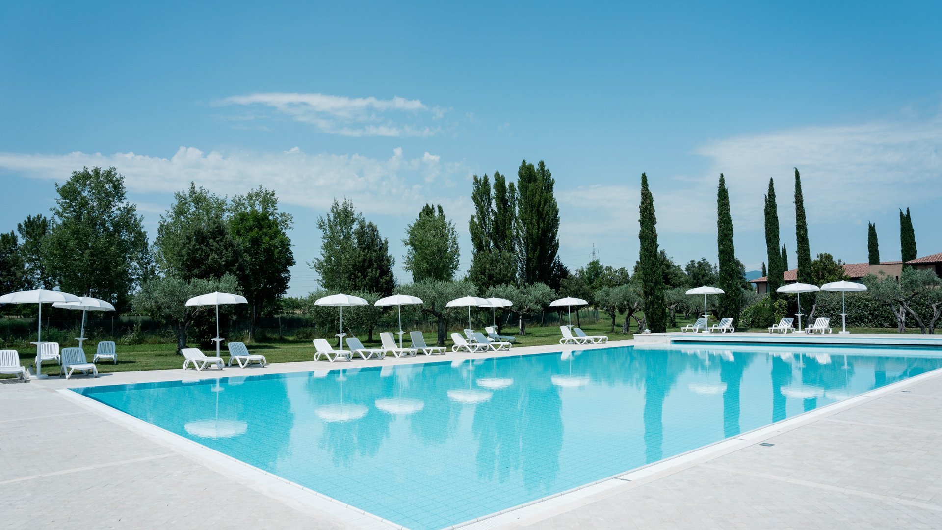 Vacanze Bike ad Assisi unico Italy bike hotels in Umbria Piscina all'aperto con lettini e ombrelloni bianchi in un giardino