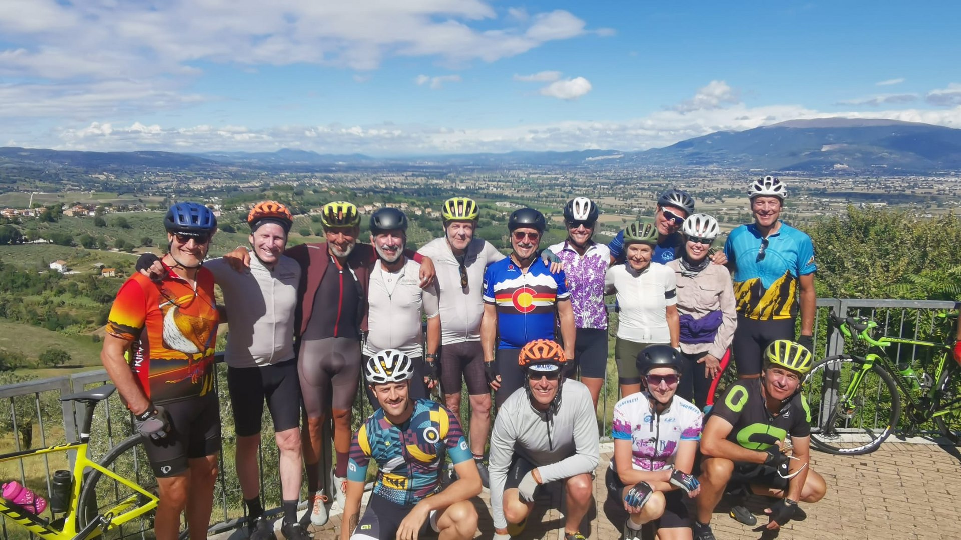 Vacanze Bike ad Assisi unico Italy bike hotels in Umbria Gruppo di ciclisti in abbigliamento sportivo con paesaggio collinare sullo sfondo