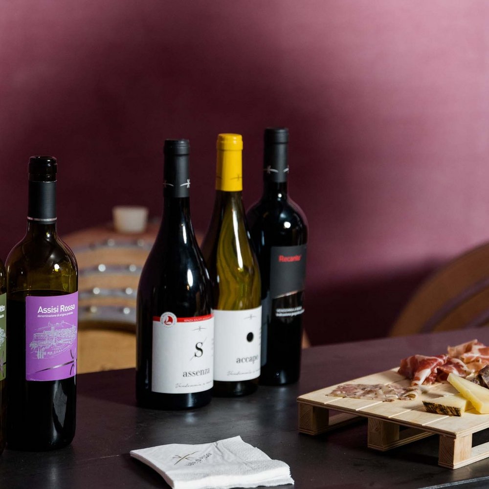 Un hotel per famiglie, in Umbria, con una marcia in più Set di bottiglie di vino e tagliere con salumi e formaggi su tavolo