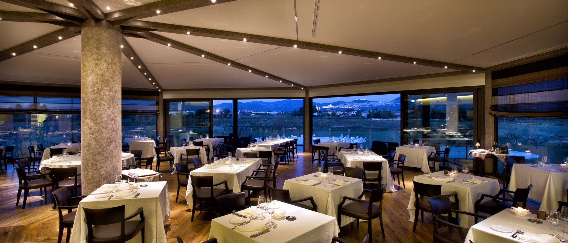 Pranzo di Pasquetta ad Assisi con Percorso SPA A Valle di Assisi, il Ristorante Recanto vi aspetta Ristorante elegante con tavoli apparecchiati e vista panoramica serale.