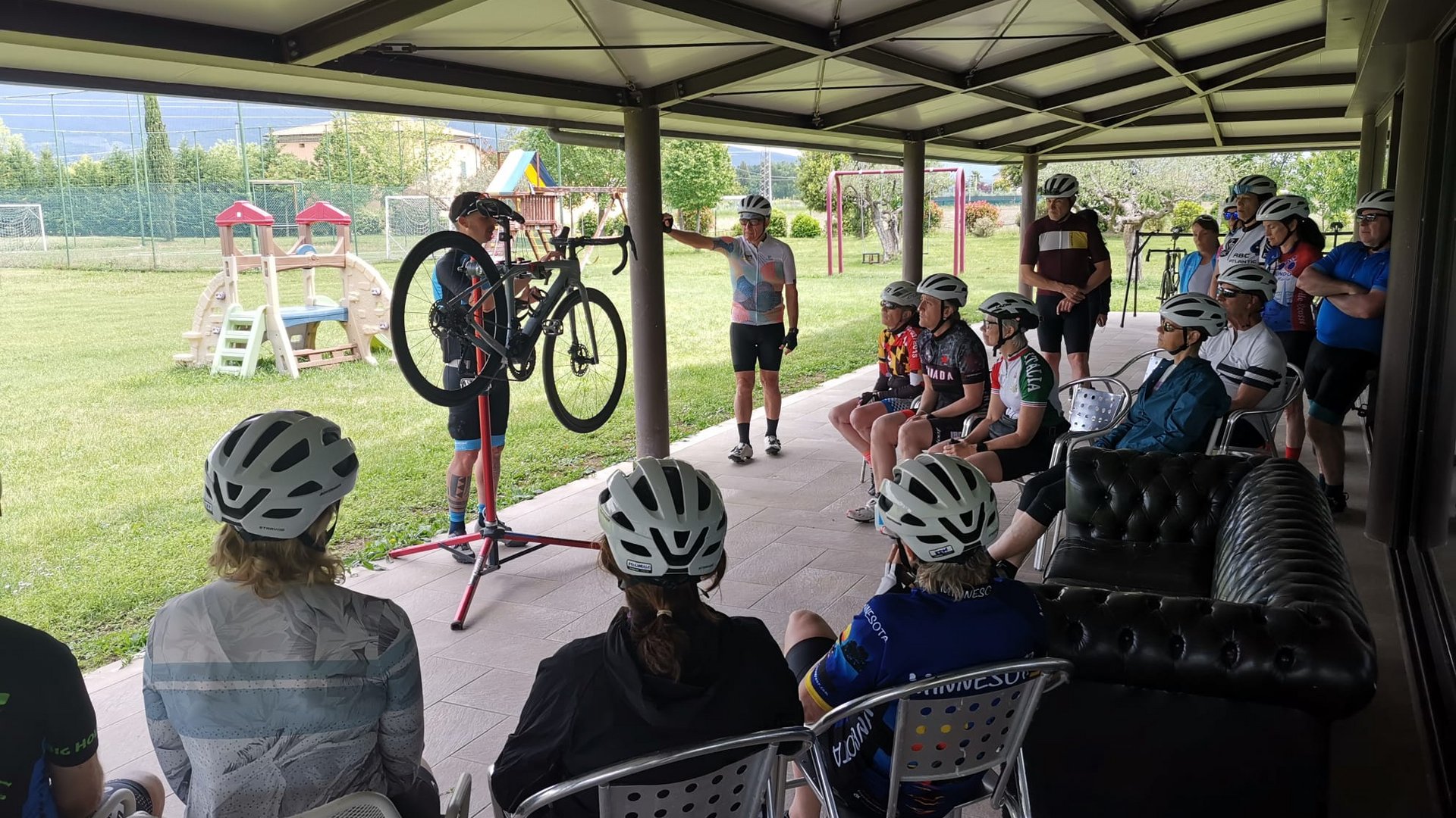 Vacanze Bike ad Assisi unico Italy bike hotels in Umbria Gruppo di ciclisti con caschi a una lezione all'aperto su una bici in riparazione