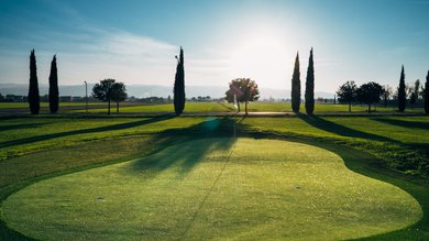 Vacanza vicino ad Assisi, Resort Hotel com Campo da Padel Tennis Bike Hotel 3 piscine campo da calcetto. Campo da golf al tramonto con alberi e sole basso all'orizzonte