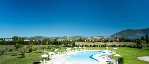 Assisi Cantico SPA - DaySPA in Umbria ad Assisi, la provincia di Perugia più bella. Percorsi Benessere Massaggi Idee Regalo per Adulti e Bambini Piscina all'aperto circondata da sdraio e ombrelloni in un paesaggio collinare
