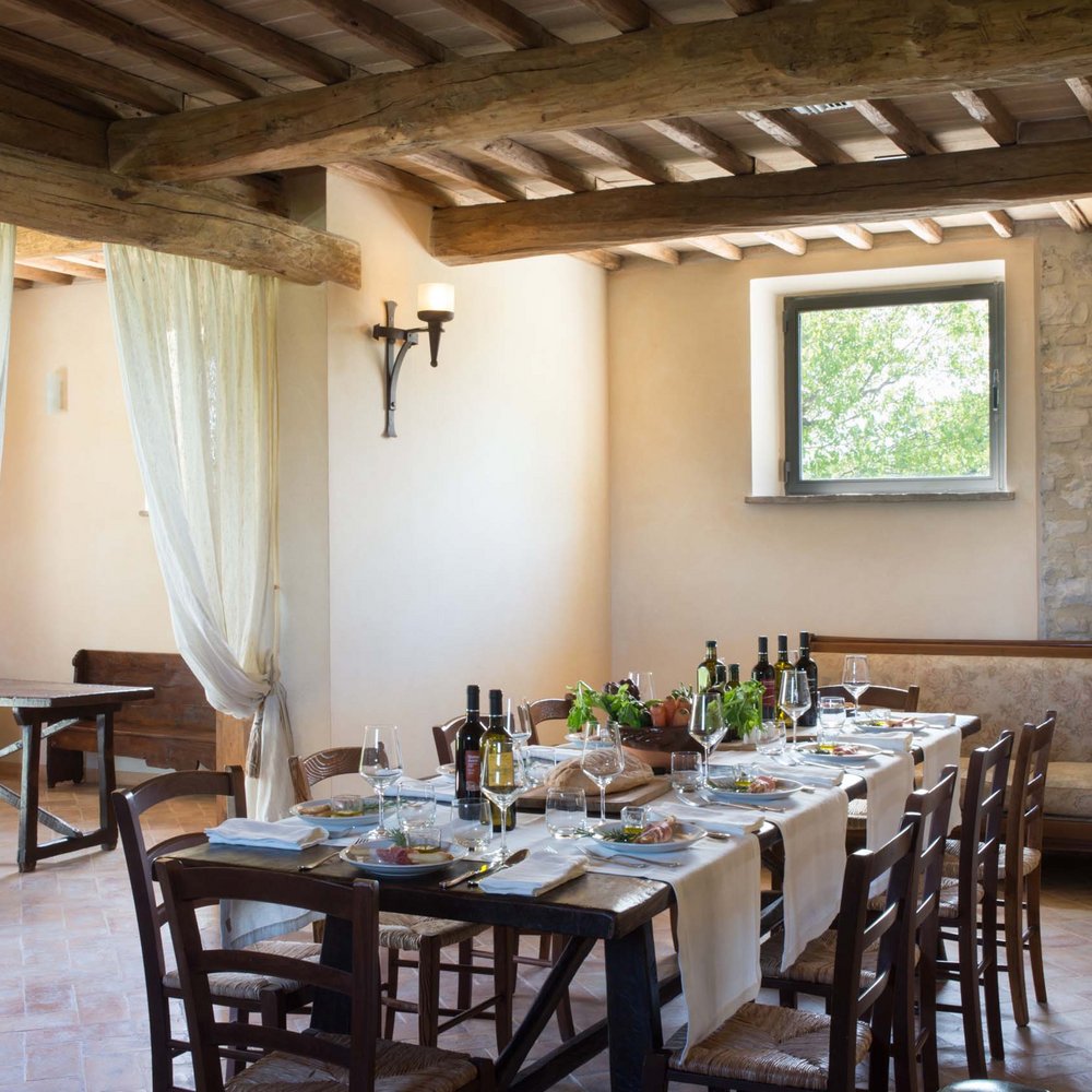 Villa ad Assisi con piscina privata, vacanze nel cuore dell'Umbria Tavola rustica apparecchiata in sala rustica con travi in legno e pietra a vista