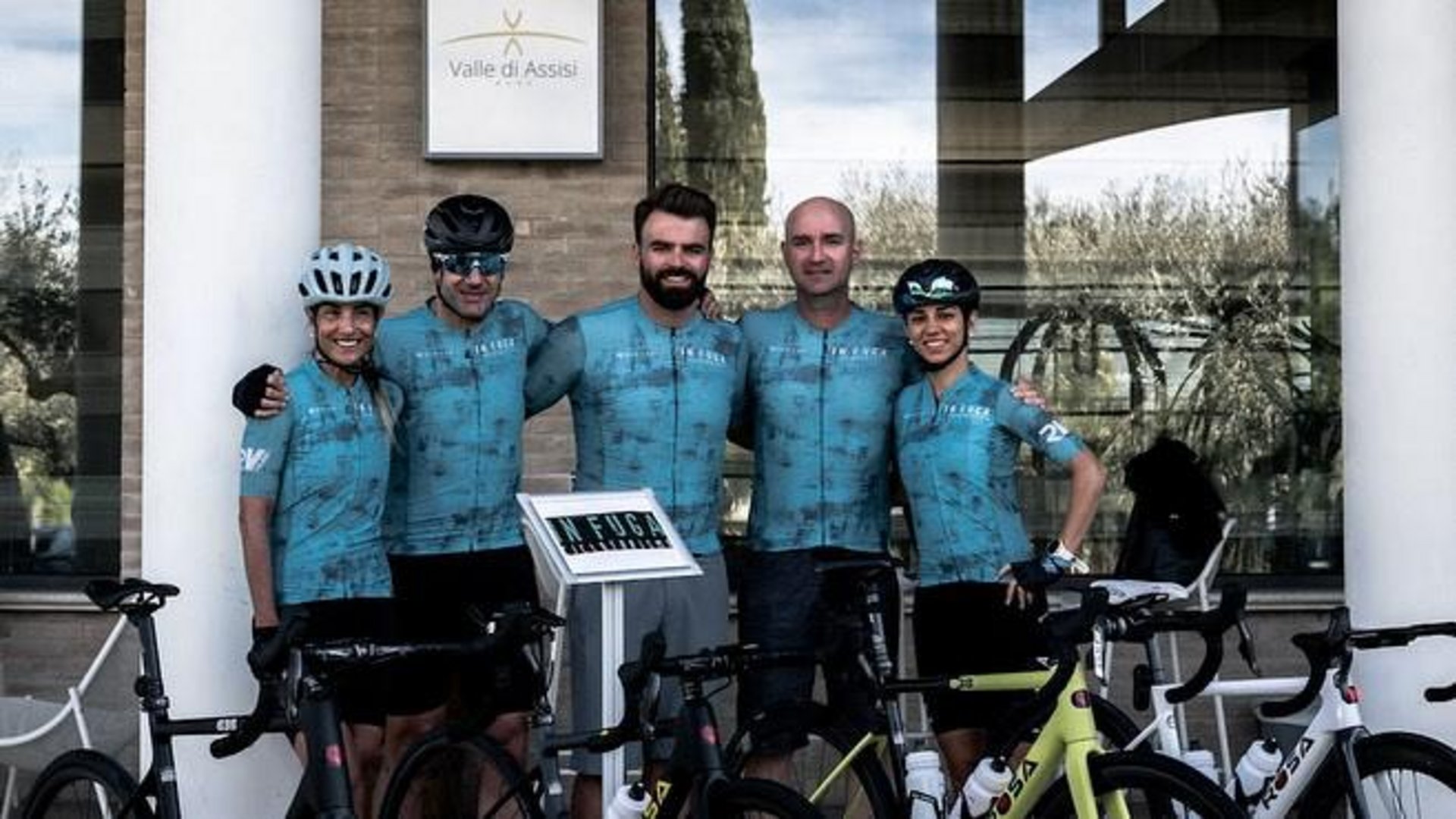 Vacanze Bike ad Assisi unico Italy bike hotels in Umbria Gruppo di ciclisti vestiti di blu posano davanti a un edificio con bici